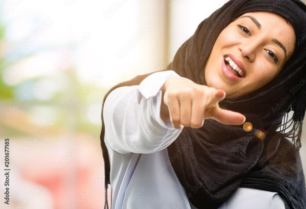 Young arab woman wearing hijab pointing to the front with finger Young arab woman wearing hijab pointing to the front with finger