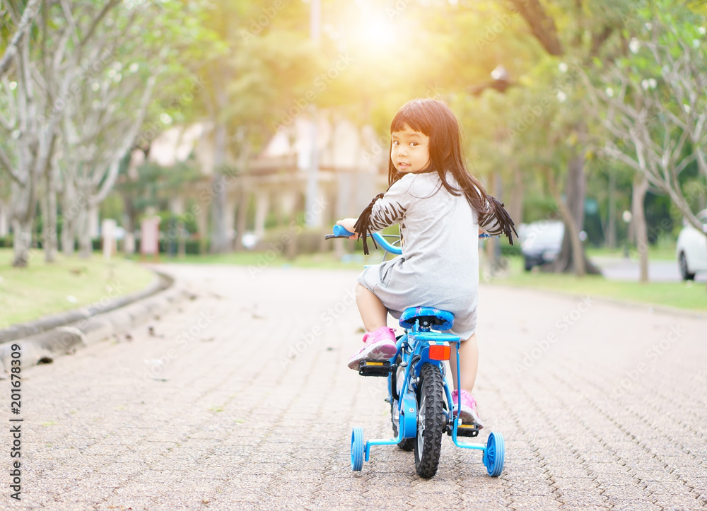 Asian children cute or kid girl cycling with smile on blue bike or bicycle on the public park with green garden and tree for fun and sport exercise with healthy on summer relax holiday and sunlight Asian children cute or kid girl cycling with smile on blue bike or bicycle on the public park with green garden and tree for fun and sport exercise with healthy on summer relax holiday and sunlight