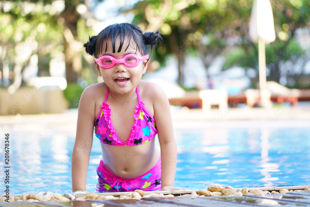 Asian children cute or kid girl wear pink bikini and goggles for swimming  and smile with