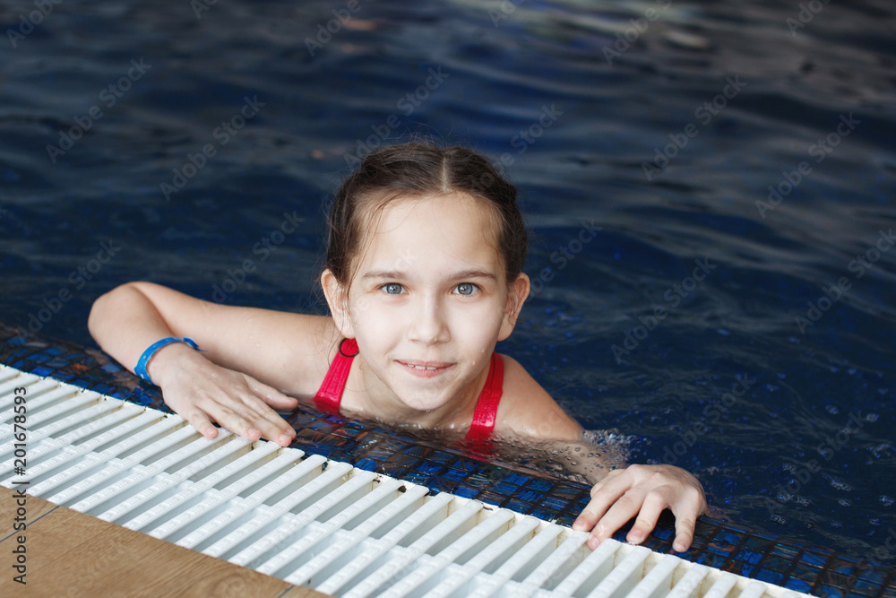 A young girl in a pool with blue water