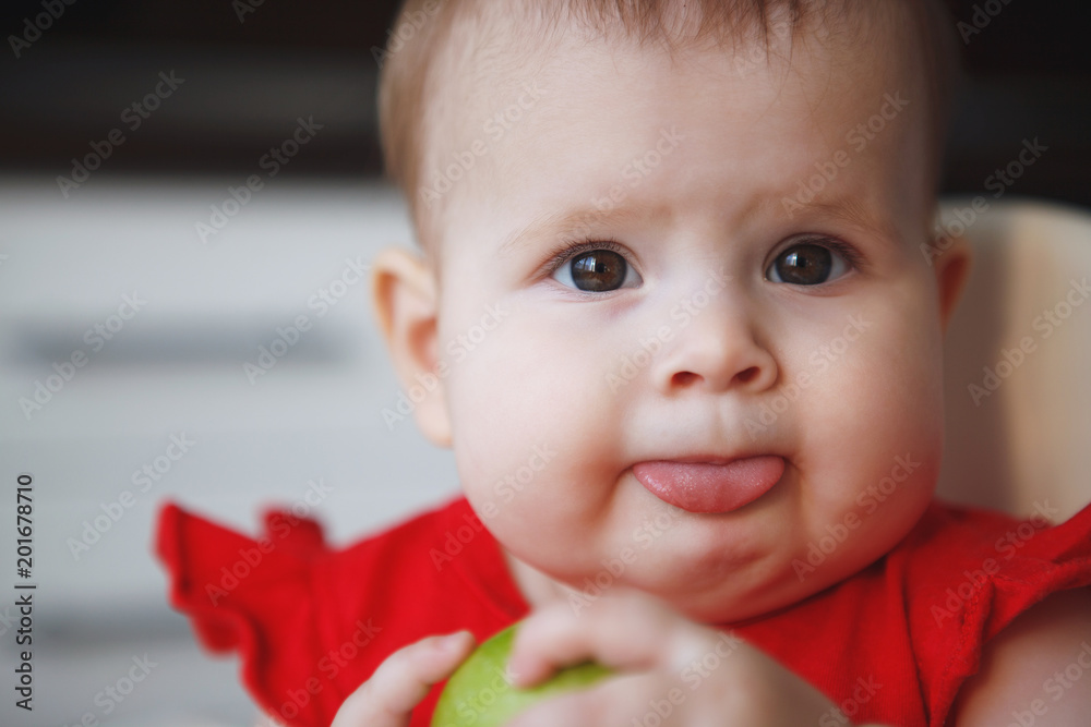 Baby in a red dress is sitting on a child's chair Baby in a red dress is sitting on a child's chair