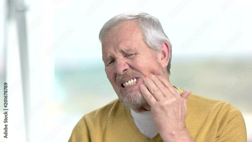 Stressed man with terrible toothache. Close up frustrated senior man touching his cheek because of strong tooth ache, blurred background. Stressed man with terrible toothache. Close up frustrated senior man touching his cheek because of strong tooth ache, blurred background.