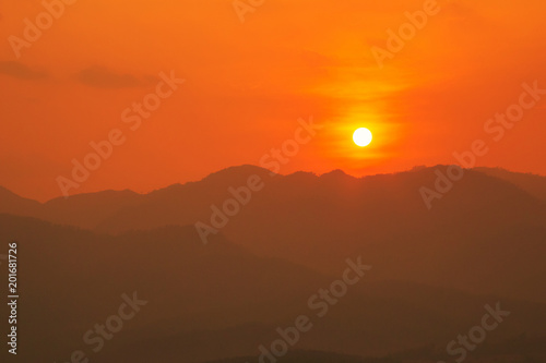 Red and orange warm sunlight in the sky during sunset with mountain range in foreground, shade and shadow, sunset sunrise