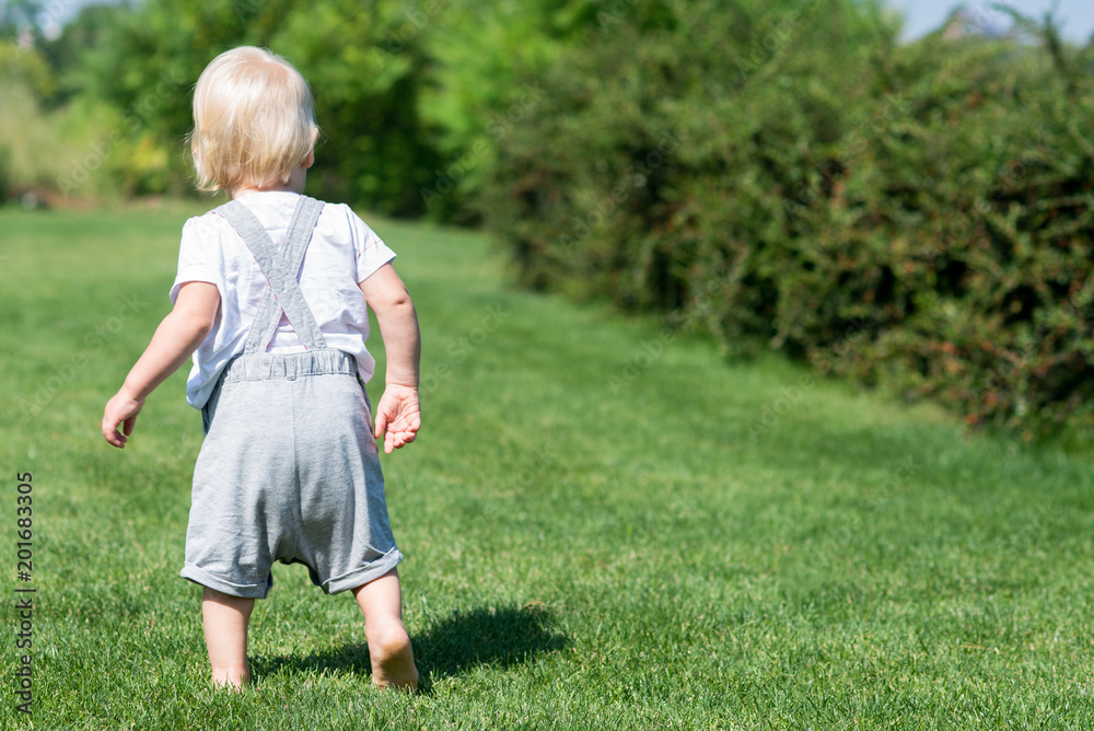 little boy runs along the green grass.