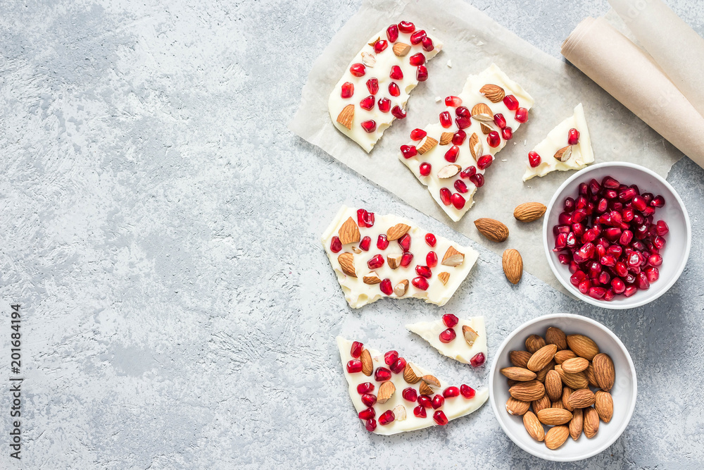 Cardamom white chocolate pomegranate nuts bark on concrete background. Top view, space for text. Cardamom white chocolate pomegranate nuts bark on concrete background. Top view, space for text.