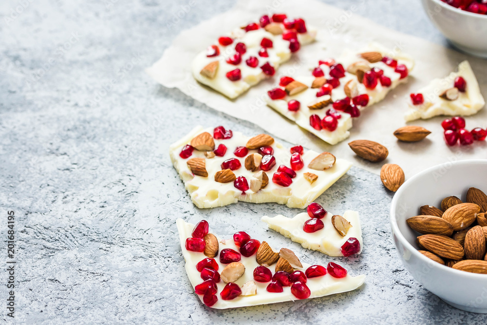 Salted white chocolate pomegranate nuts bark on concrete background. Selective focus, space for text. 