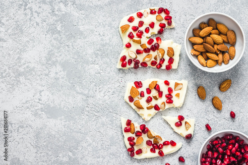 Gluten free white chocolate pomegranate nuts bark on concrete background. Top view, copy space.