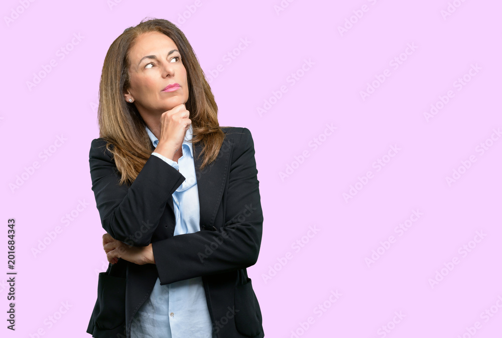 Middle age business woman thinking and looking up expressing doubt and wonder Middle age business woman thinking and looking up expressing doubt and wonder