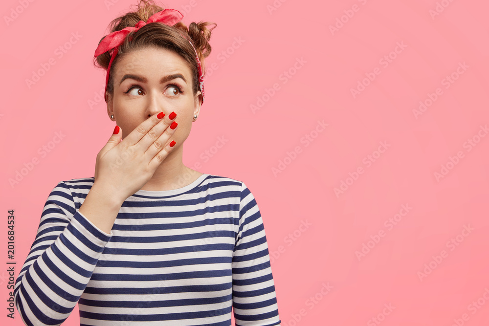 Frightened female in shock, has red manicure, nice make up, wears striped clothing, looks with scared expression upwards, isolated over pink background with blank copy space for your advertisment Frightened female in shock, has red manicure, nice make up, wears striped clothing, looks with scared expression upwards, isolated over pink background with blank copy space for your advertisment