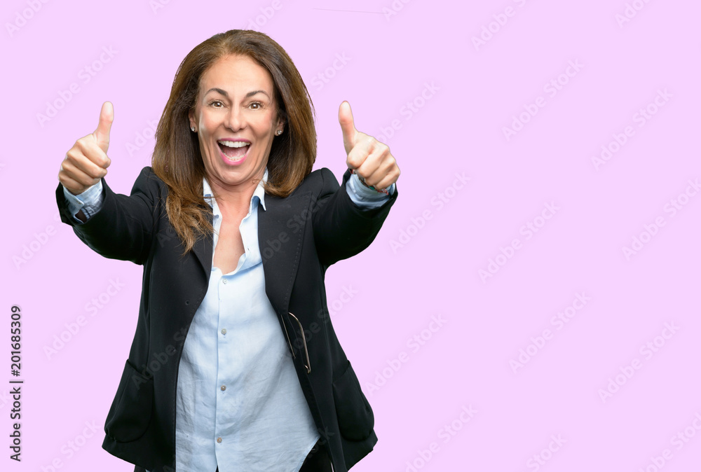 Middle age business woman stand happy and positive with thumbs up approving with a big smile expressing okay gesture Middle age business woman stand happy and positive with thumbs up approving with a big smile expressing okay gesture