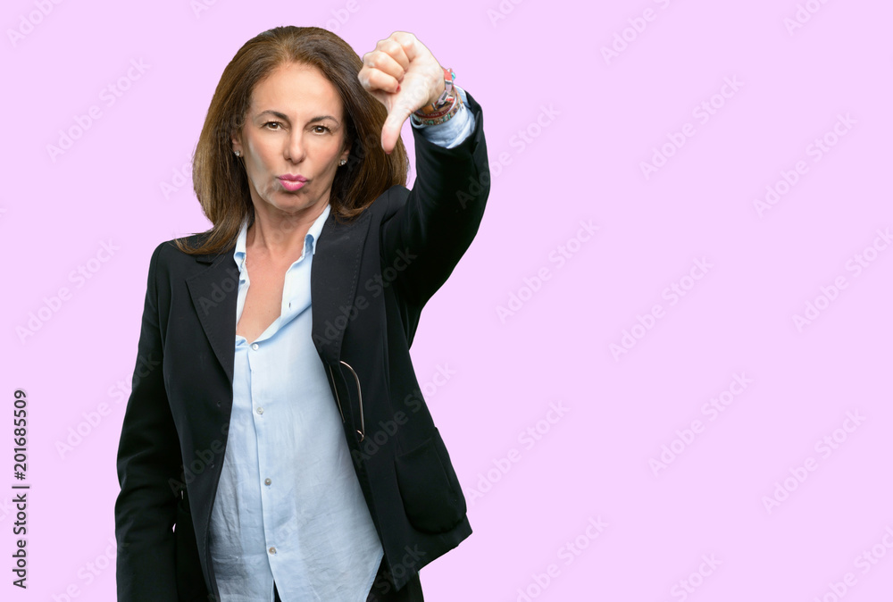 Middle age business woman showing thumbs down unhappy sign of dislike, negative expression and disapproval Middle age business woman showing thumbs down unhappy sign of dislike, negative expression and disapproval