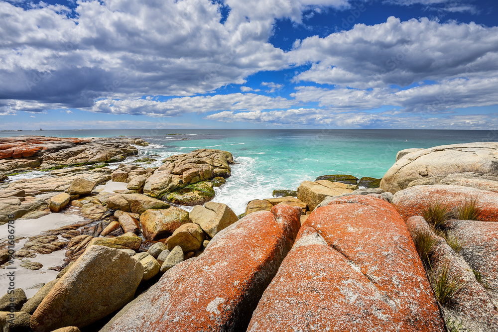 Beautiful sunny summer coast view from Bay Of Fires to blue Tasman Sea with crystal clear water surrounded by red orange colorful shore rocks and white sandy beach, Binalong Bay, Tasmania, Australia