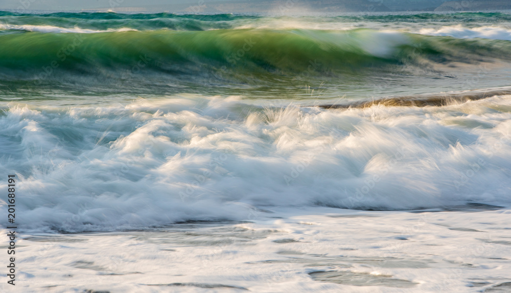 Rocky seashore with wavy ocean and wind waves crashing on the rocks Rocky seashore with wavy ocean and wind waves crashing on the rocks