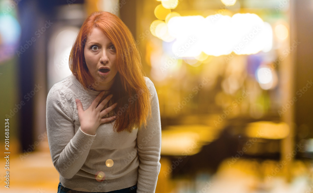 Fototapeta premium Beautiful young redhead woman happy and surprised cheering expressing wow gesture at night