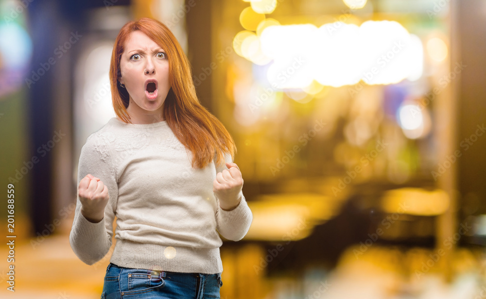 Beautiful young redhead woman happy and excited celebrating victory expressing big success, power, energy and positive emotions. Celebrates new job joyful at night Beautiful young redhead woman happy and excited celebrating victory expressing big success, power, energy and positive emotions. Celebrates new job joyful at night