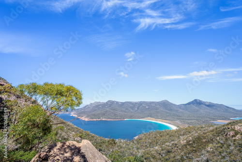 Wonderful view to stunning sandy beach blue turqouise water on warm sunny day with blue sky relaxing after hiking on top Mount Amos, Wineglass, Freycinet National Park, Coles Bay, Tasmania, Australia