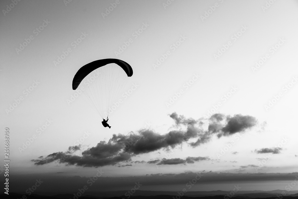 Beautiful shot of a paraglider silhouette flying over Monte Cucco (Umbria, Italy), with sunset on the background Beautiful shot of a paraglider silhouette flying over Monte Cucco (Umbria, Italy), with sunset on the background