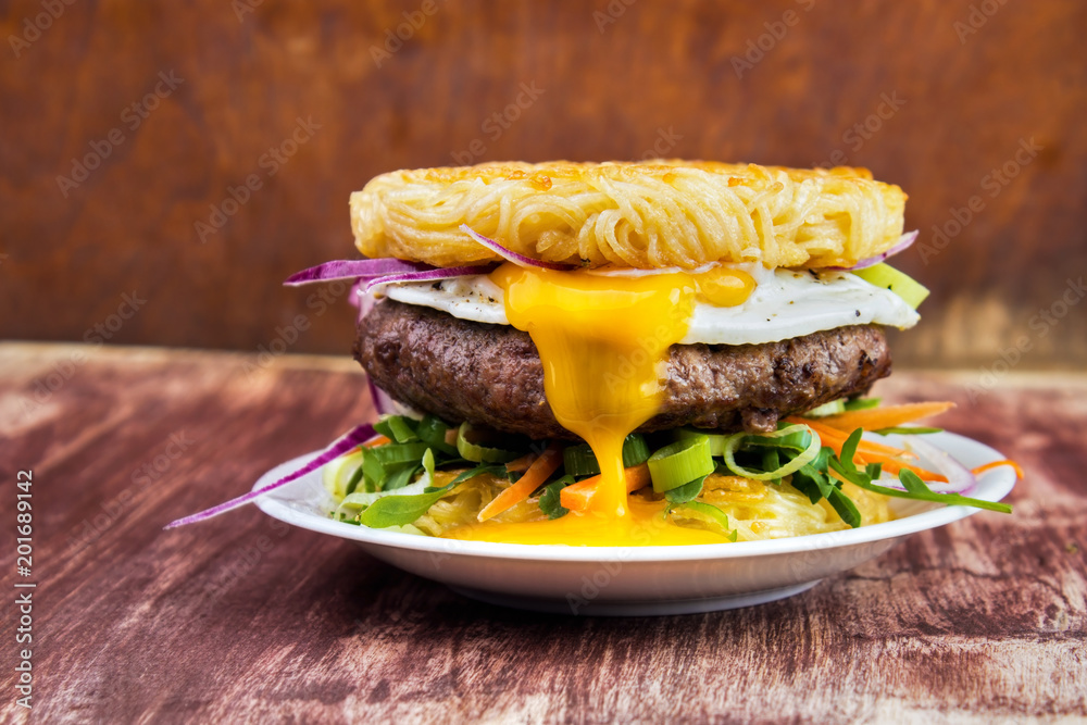 Ramen beef burger with egg, carrot strips , chives , red onion and fried egg , bun made of noodles