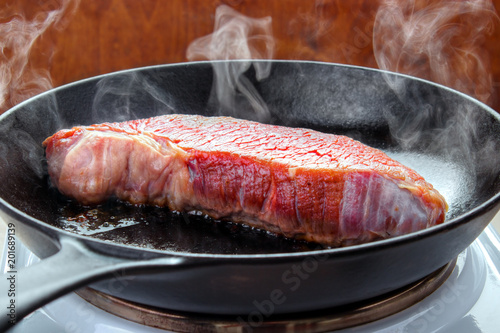 Searing beef brisket steak on the electric stove with hot cast iron skillet