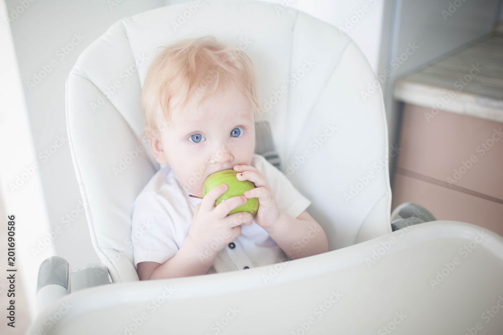 A baby breast eats a green apple A baby breast eats a green apple