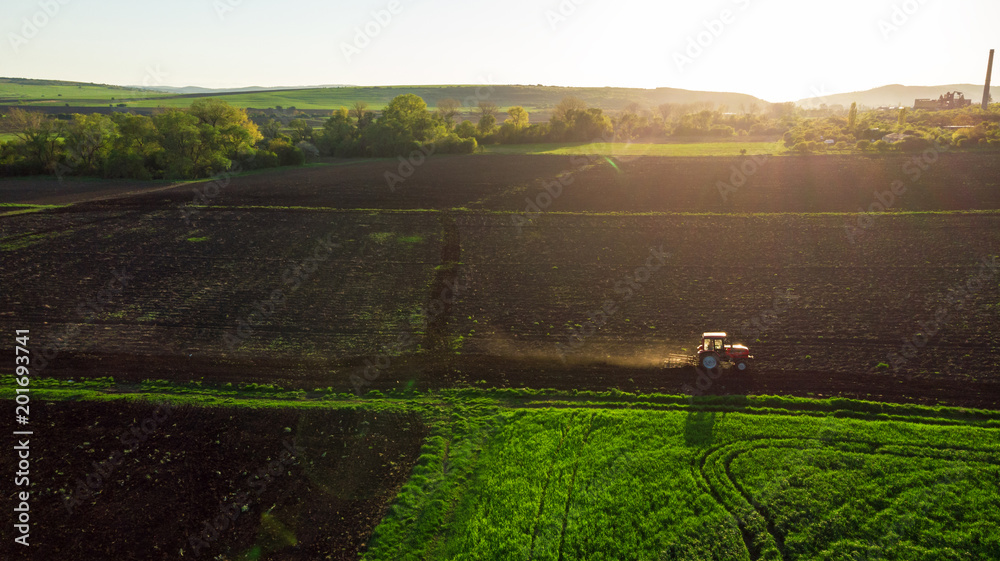 Naklejka premium Aerial view of tractor at sunset.