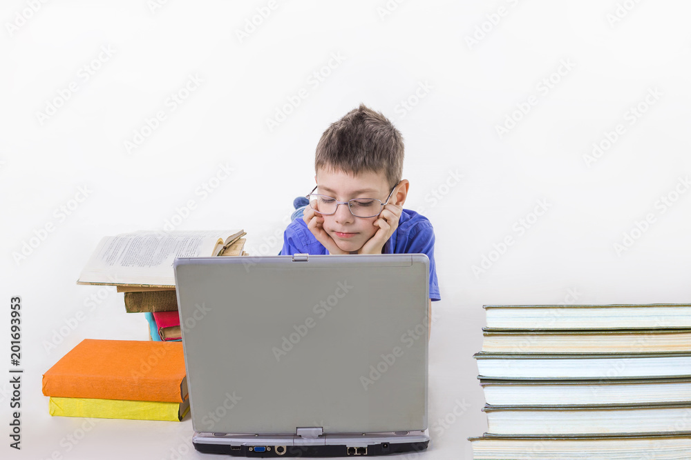 Portrait of cute schoolboy sitting with books and typing on laptop keyboard Portrait of cute schoolboy sitting with books and typing on laptop keyboard