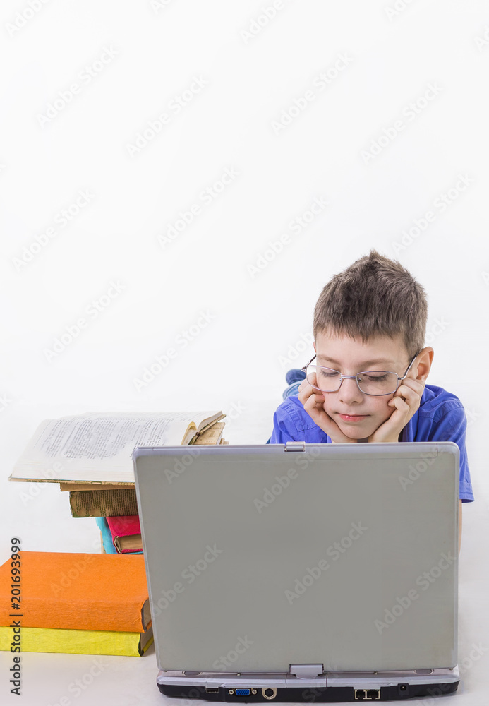 Portrait of cute schoolboy sitting with books and typing on laptop keyboard Portrait of cute schoolboy sitting with books and typing on laptop keyboard