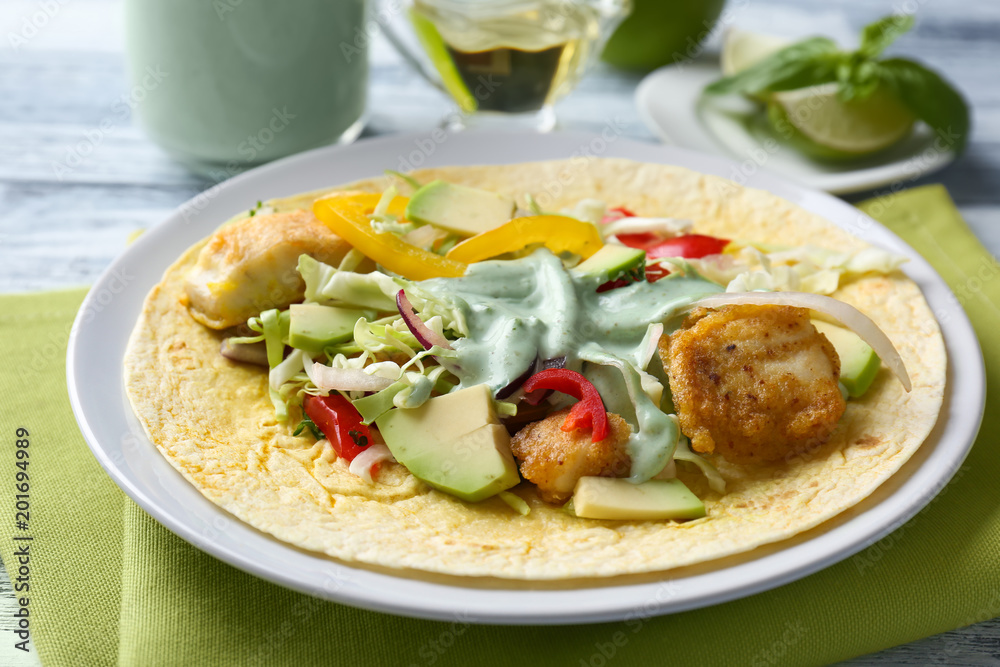 Plate with tasty fish taco and creamy sauce on kitchen table Plate with tasty fish taco and creamy sauce on kitchen table