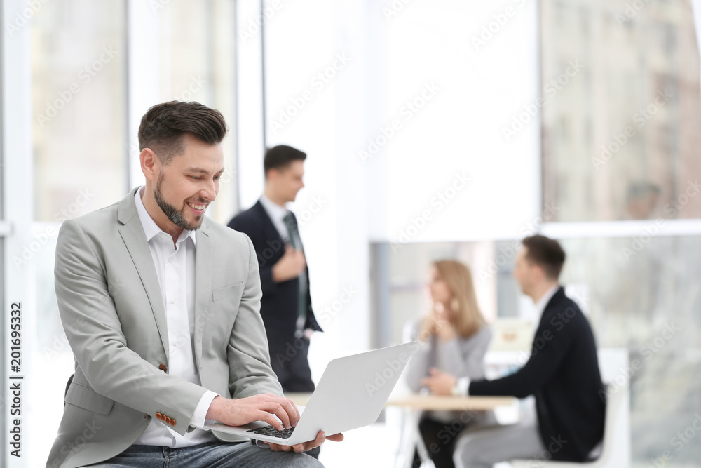 Portrait of handsome young businessman with laptop in office Portrait of handsome young businessman with laptop in office