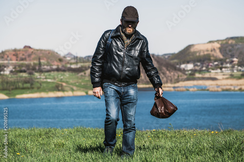 man with beard goes along grass against terricon backgrounds photo