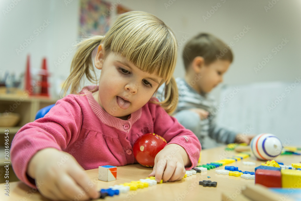 View of child in kindergarten plying with wooden toys View of child in kindergarten plying with wooden toys