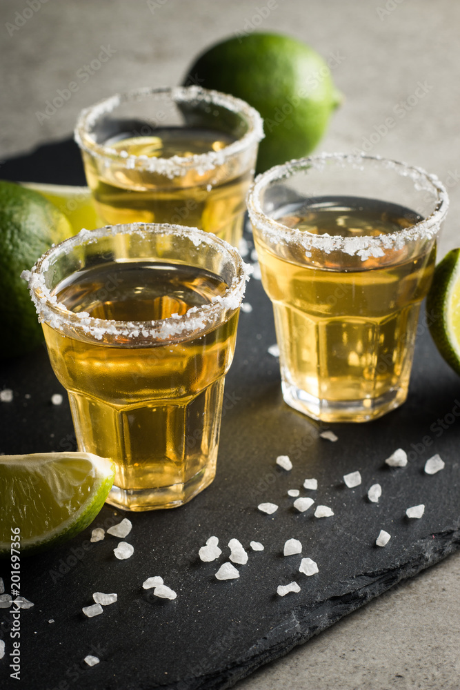 Macro photo of shots of gold Mexican tequila with lime and salt on wooden rustic background. Alcoholic drink concept. selective focus. Macro photo of shots of gold Mexican tequila with lime and salt on wooden rustic background. Alcoholic drink concept. selective focus.