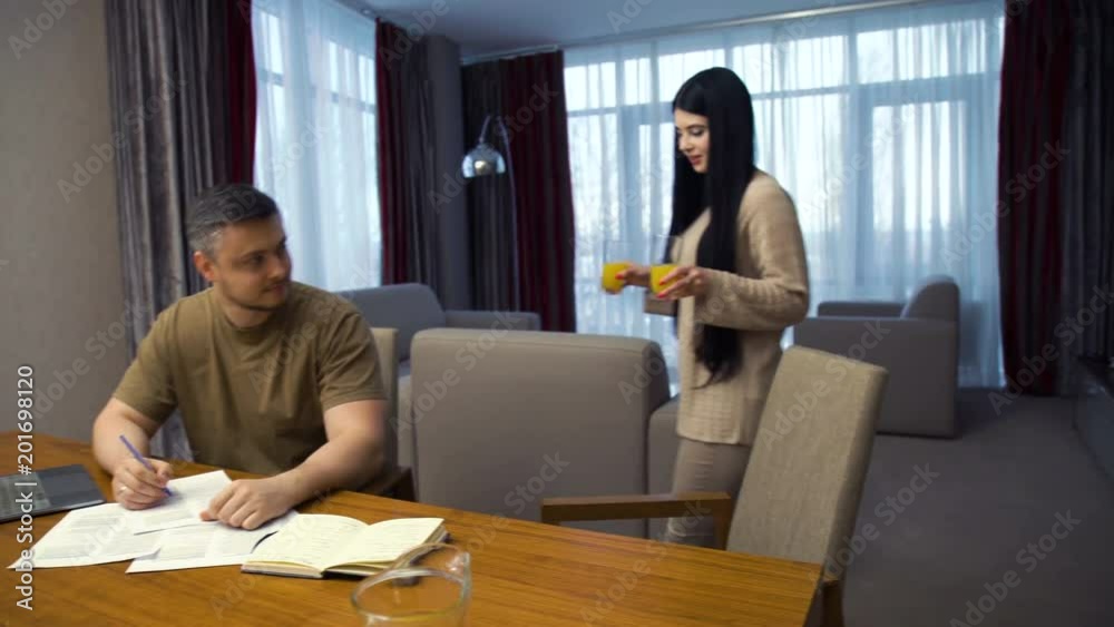family care and communication. couple loving relationship. woman brings juice drink to her working husband. family care and communication. couple loving relationship. woman brings juice drink to her working husband.