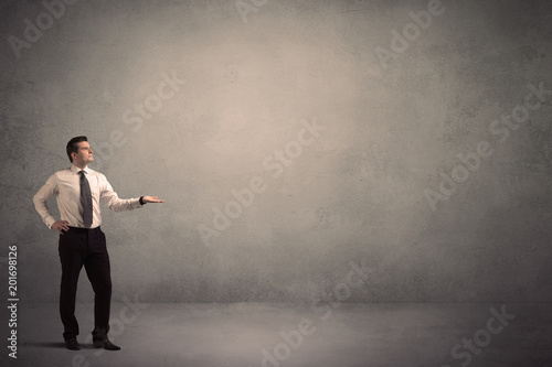 Caucasian businessman standing in front of a grunge, blank wall