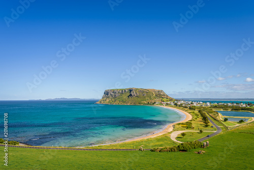 Fototapeta Naklejka Na Ścianę i Meble -  Stunning view point to big old volcanic rock mountain top called The Nut with blue turquoise water beach bay and green grass lands on warm sunny clear sky day, Stanley, North-West, Tasmania, Australia
