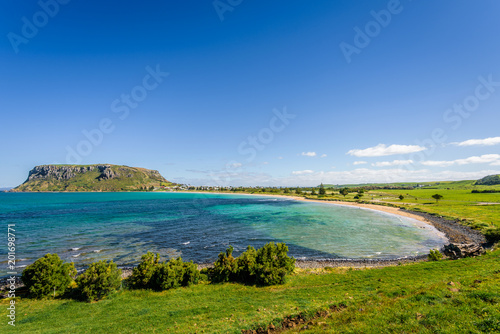 Stunning view point to big old volcanic rock mountain top called The Nut with blue turquoise water beach bay and green grass lands on warm sunny clear sky day  Stanley  North-West  Tasmania  Australia