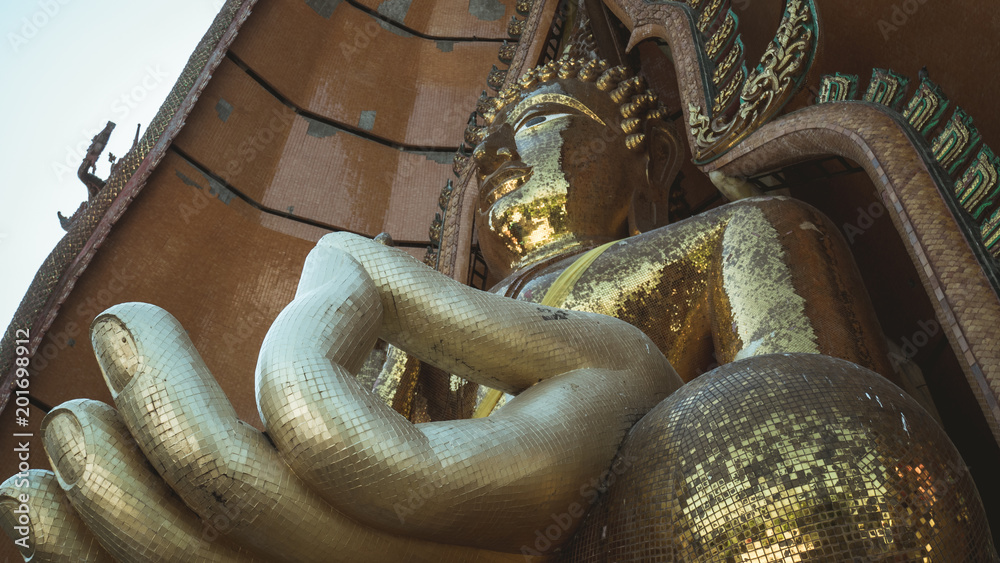 Cinematic style. Statue of a large golden Buddha in a sitting position at Wat Tham Suea or Tham Suea temple, Kanchanaburi, Thailand.