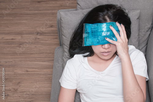 Top view of Asian woman with cold pack on her forehead for relief fever headaches and migraines