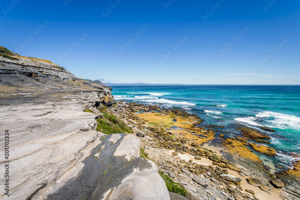 Amazing view to stunning rocky sandy beach deep blue water of southern ocean antarctica on warm sunny day with blue sky after hiking on to South Cape Bay, South-West National Park, Tasmania, Australia