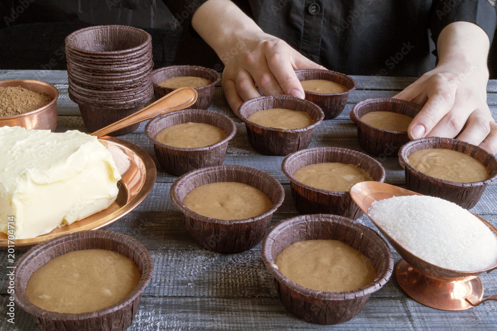 Fototapeta premium Women's hands preparing homemade chocolate cupcakes.