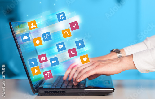 Wallpaper Mural Hand using laptop with colorful fast moving application icons and symbols concept
 Torontodigital.ca