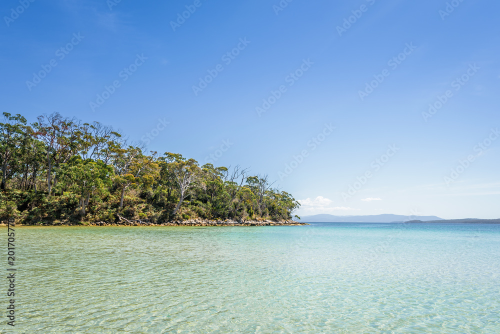 Amazing view to small paradise like island sandy beach with turquoise blue water and green shore jungle forest on warm sunny clear sky day camping ground, Jetty Beach Bruny Island, Tasmania, Australia