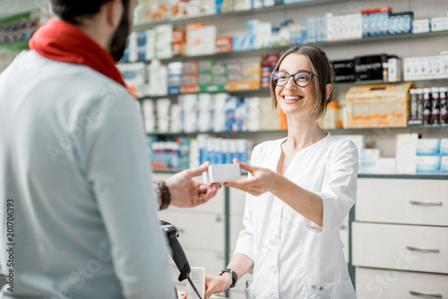 Pharmacist selling medications in the pharmacy store photo
