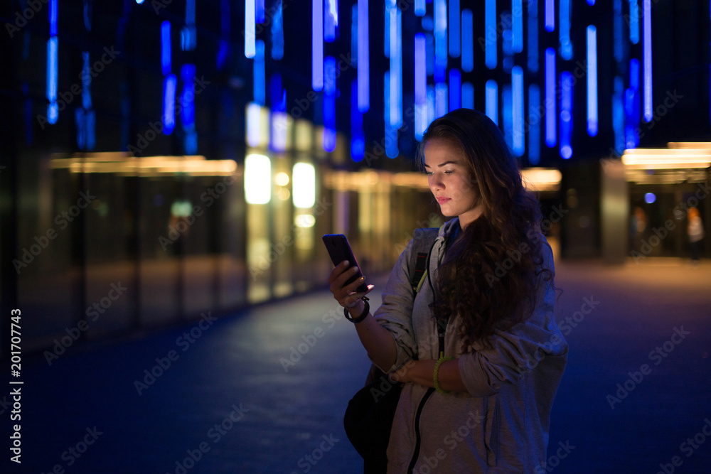 Beautiful young stylish woman walking in the night city streets using ...