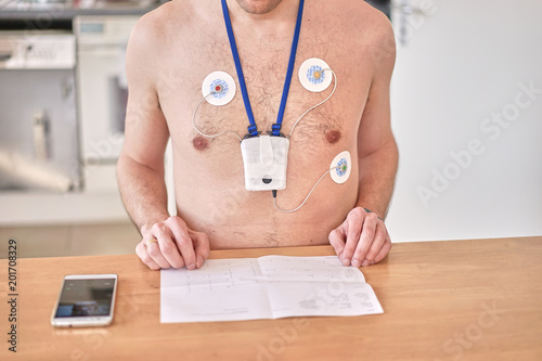 Photography Man wearing 24 hrs electrocardiogram monitor device on his chest