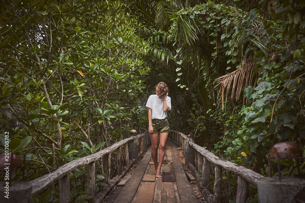 Traveling girl on the wooden bridge. Pretty young woman in the jungle. Summer lifestyle and adventure photo Traveling girl on the wooden bridge. Pretty young woman in the jungle. Summer lifestyle and adventure photo