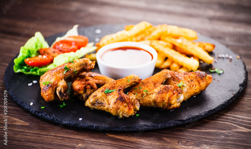 Grilled chicken wings, chips and vegetables