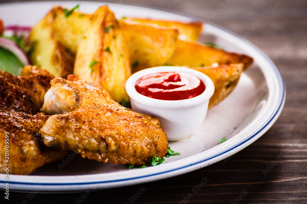 Grilled chicken wings, chips and vegetables Grilled chicken wings, chips and vegetables