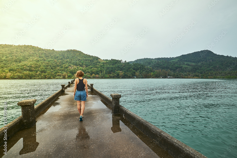 Traveling girl on the pier. Pretty young woman on the bridge. Summer lifestyle and adventure photo