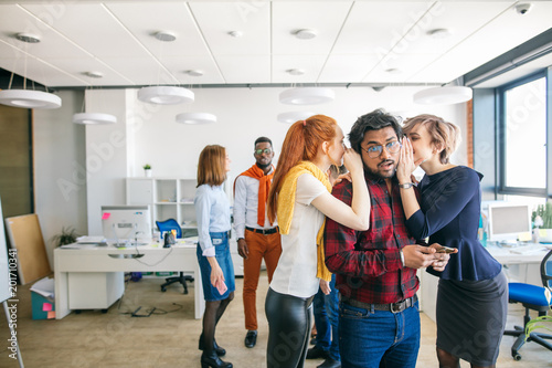 Businesswomen in casual clothes gossiping about colleagues in office. tell tails. spill dirt